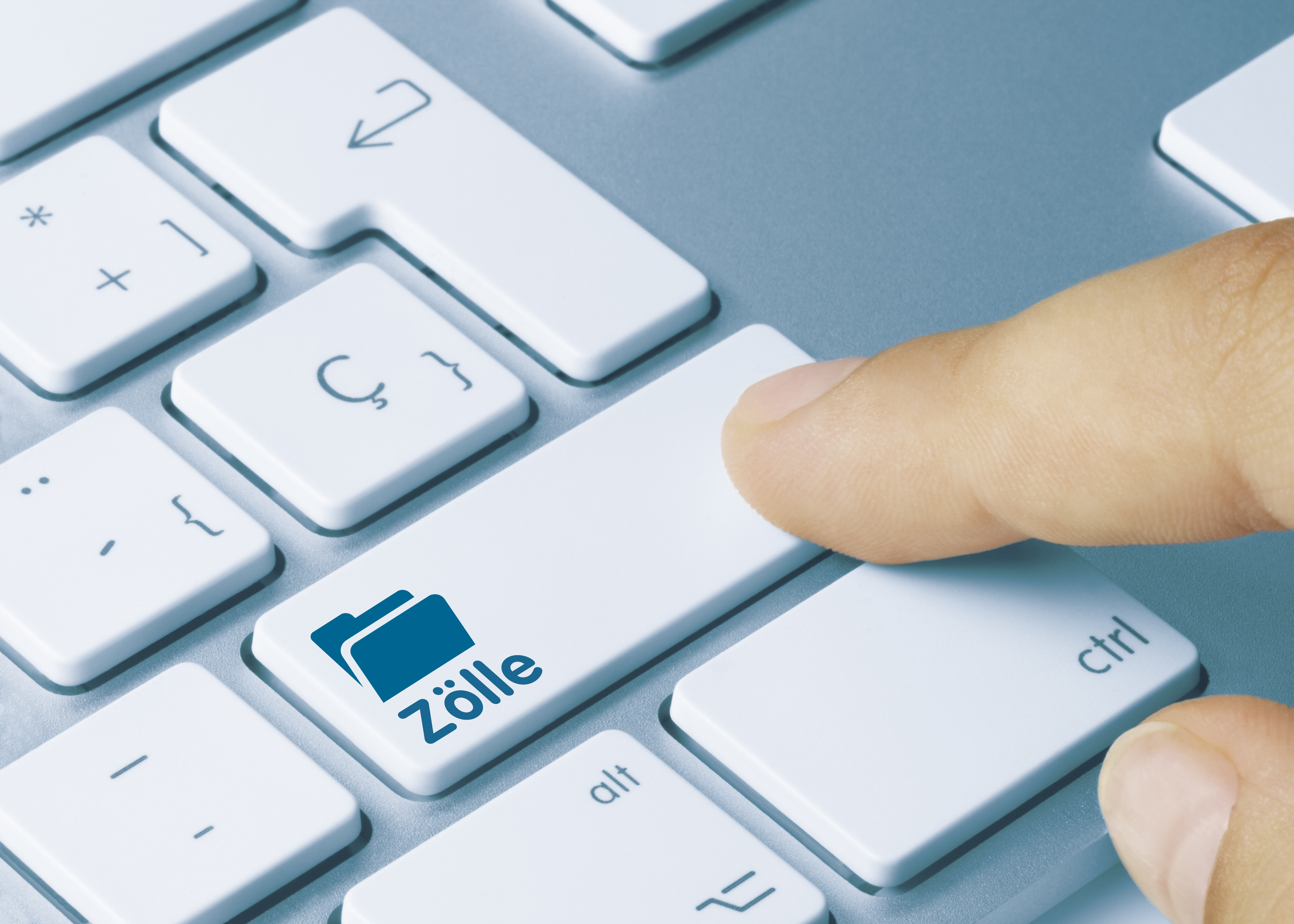 Mann zeigt mit Finger auf eine weisse Tastatur mit Taste Zölle