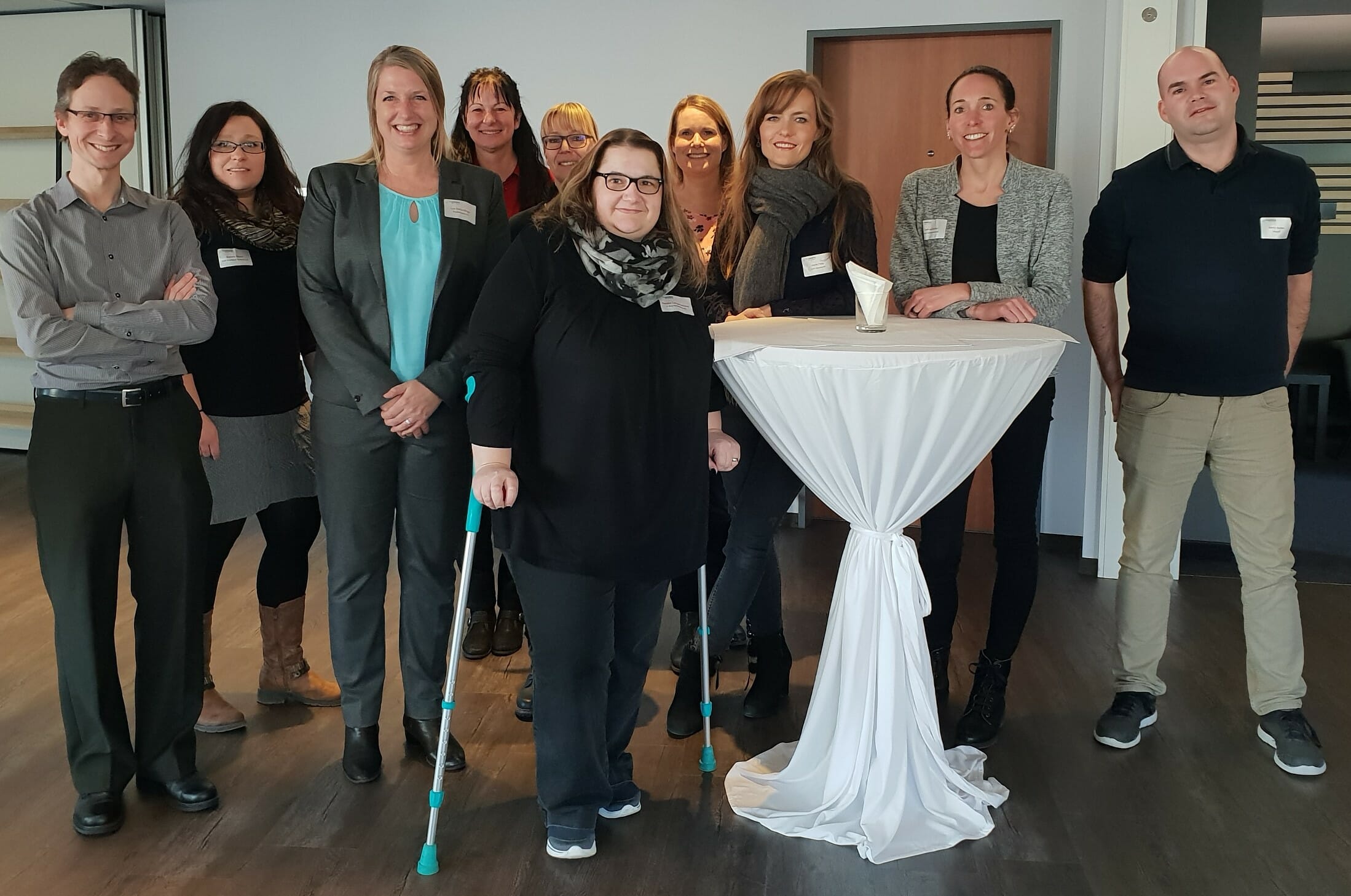 Zufriedene Teilnehmer eines Zollseminars von FineSolutions AG stehen mit Lea Derendinger und Betreuerin Simone Meierhofer in einer Pause vor einem Tisch