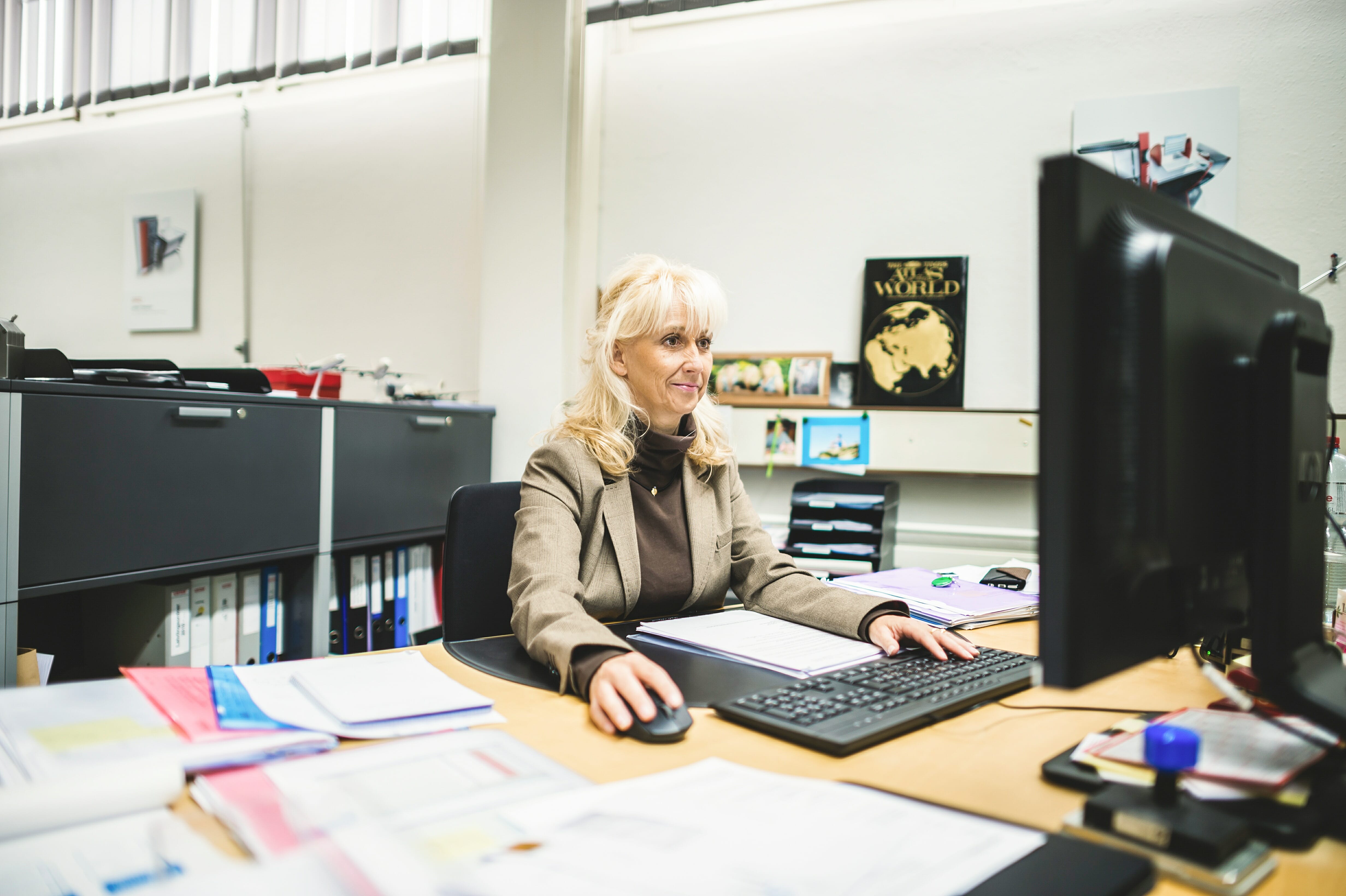 Mitarbeiterin sitzt am Pult vor ihrem PC und bedient ExpoWin von finesolutions