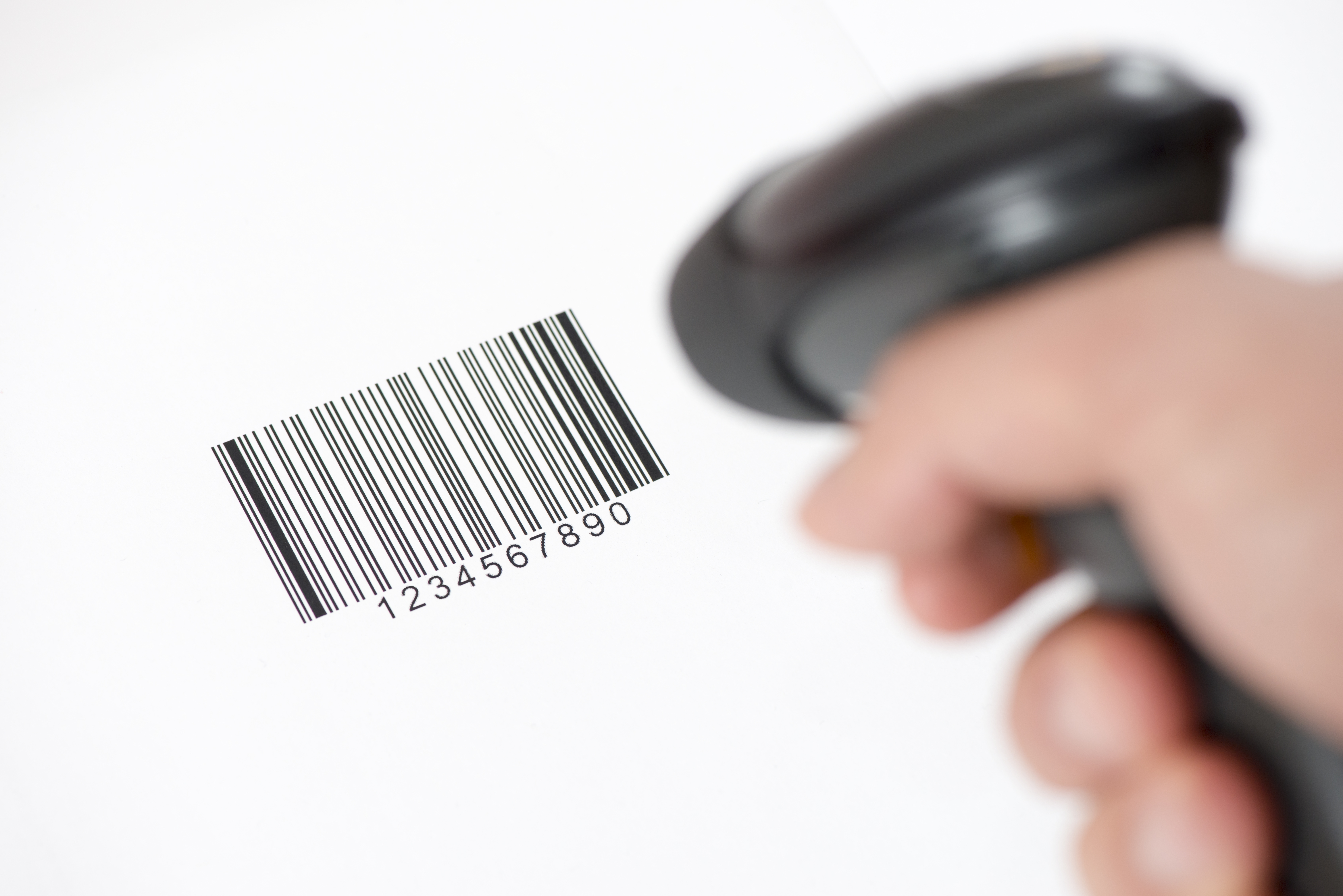 Mann mit Scanner in der Hand scannt einen Barcode auf weissem Papier ab