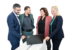 Bild von vier Personen nebeneinander stehend, die eine Diskussion führen und zeitgleich in ein Laptop blicken