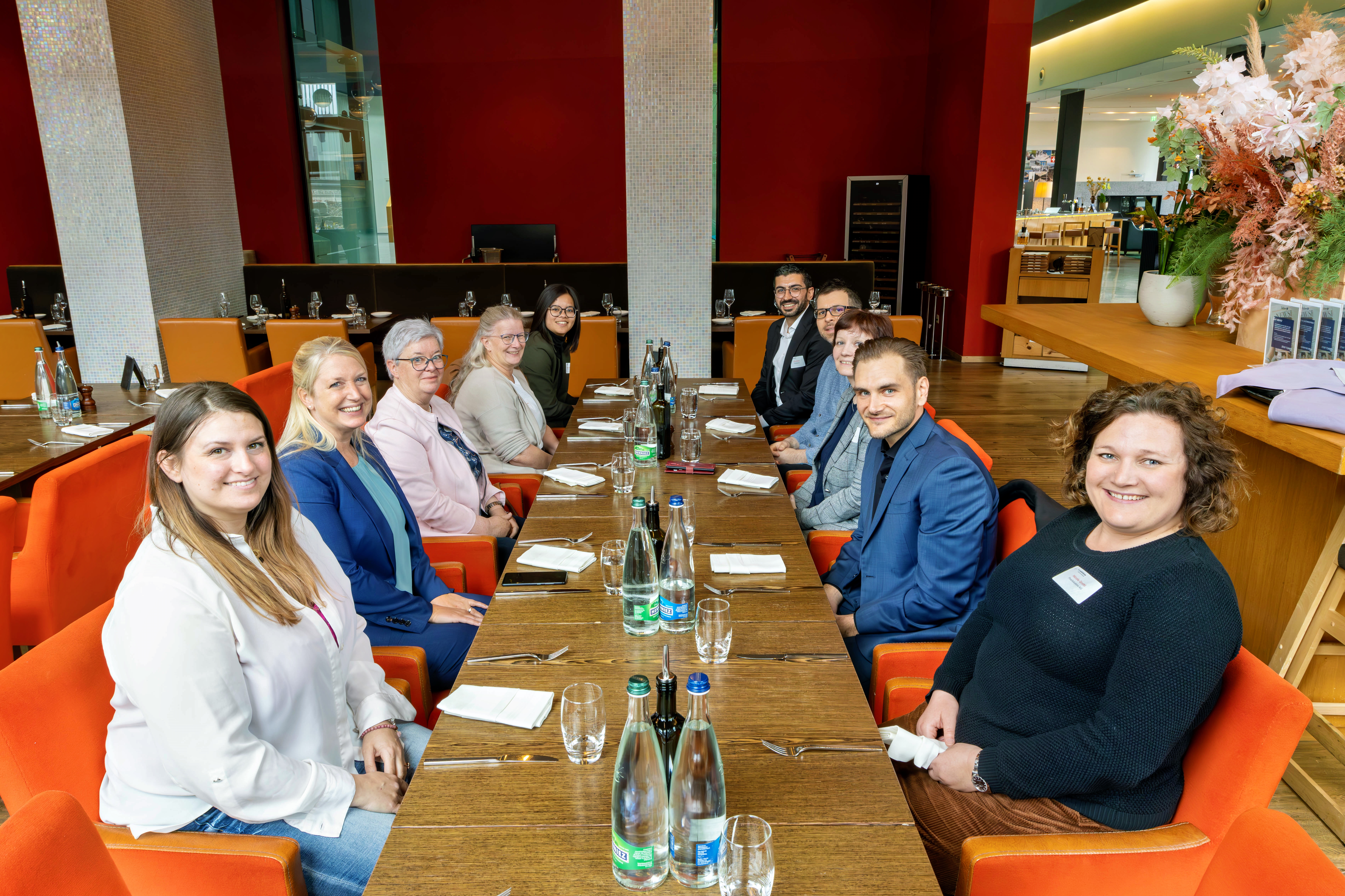 Personen eines Zollseminars sitzen am gemeinsamen Mittagstisch und schauen in die Kamera