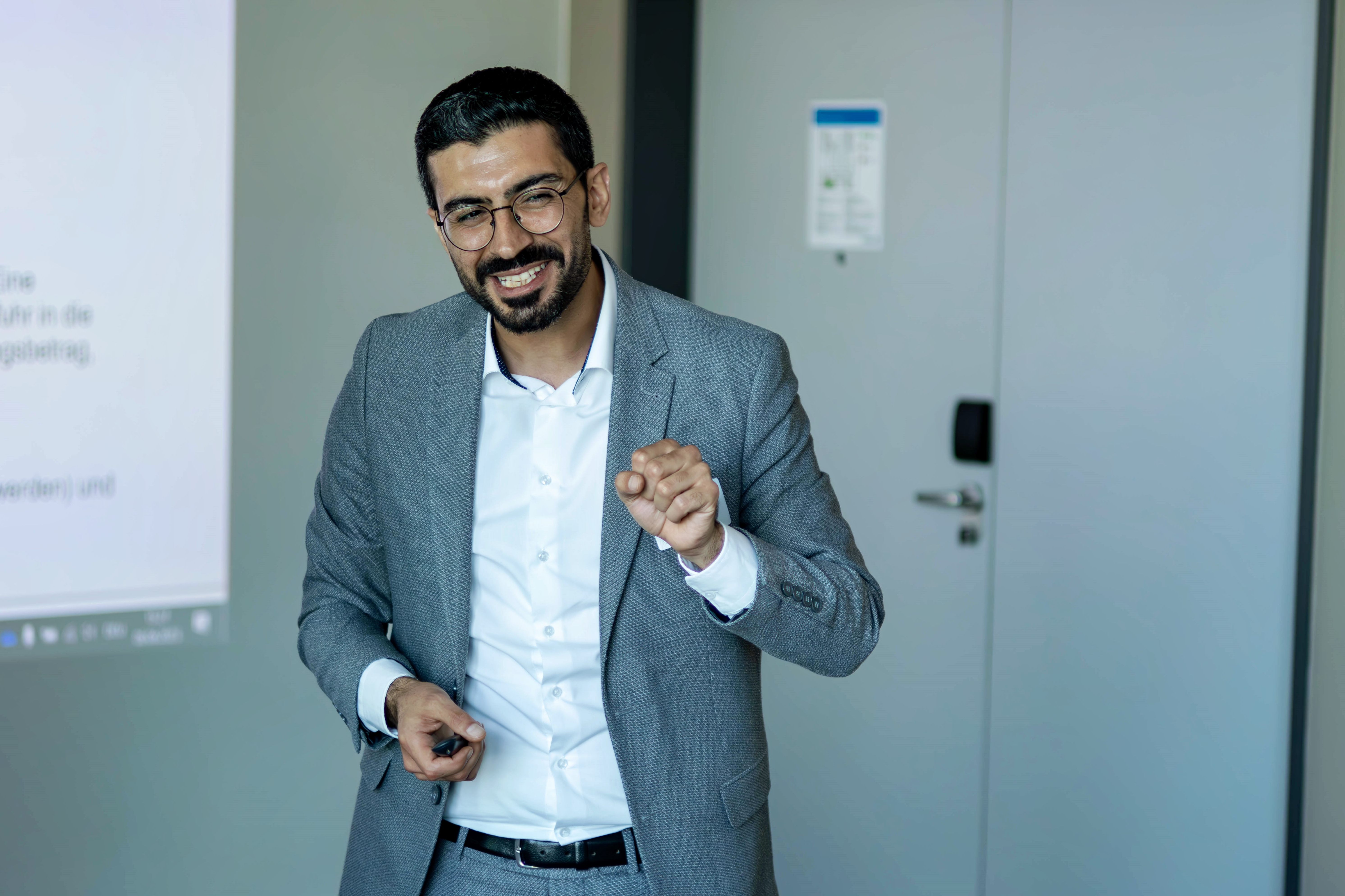 Olcay Erden von FineSolutions steht als Zoll Seminarleiter im Seminarraum vor der Folie und gibt Tipps