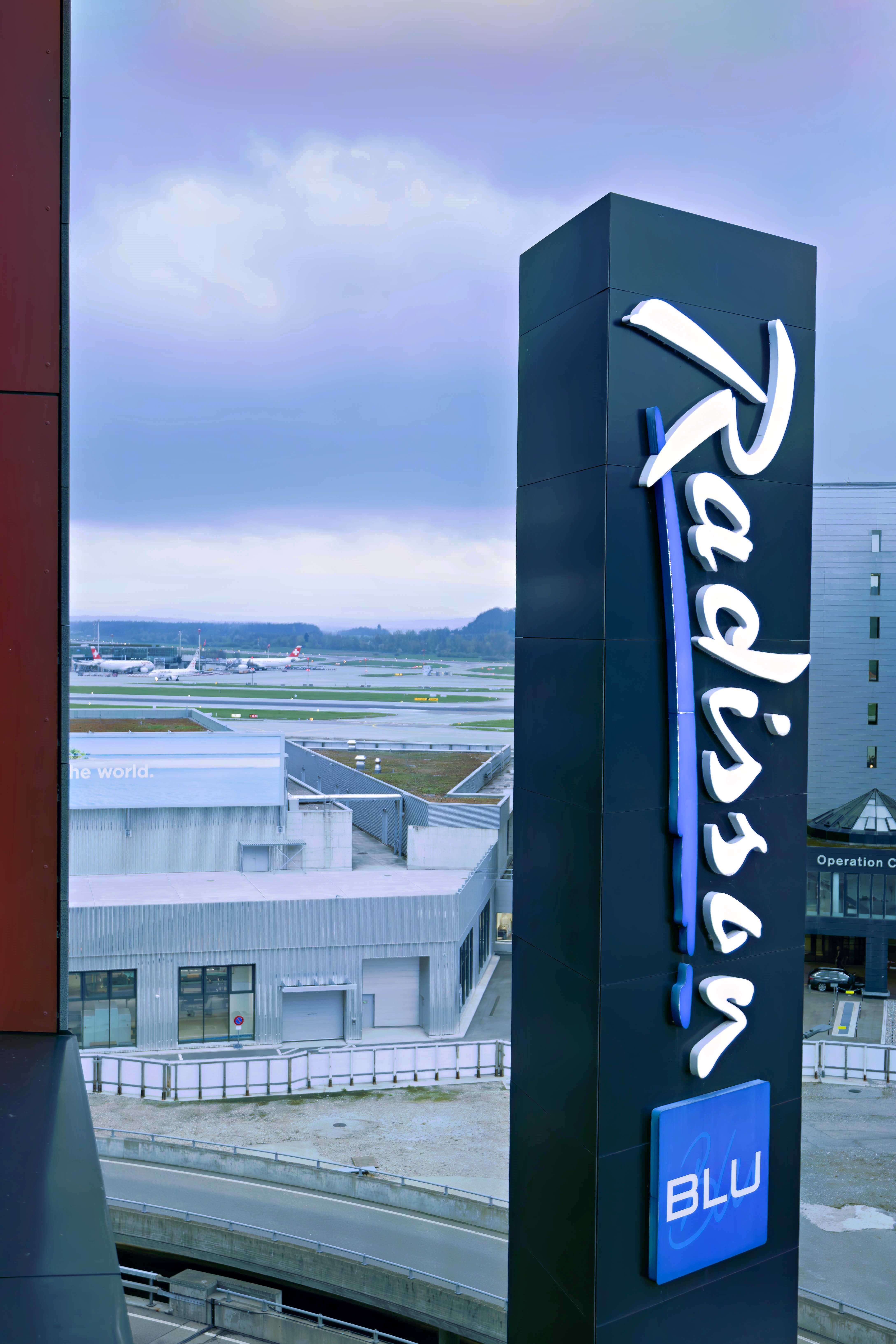 Leuchtreklame Radisson Blu am Zürcher Flughafen mit Ausblick auf das Parkfeld mit Flugzeugen